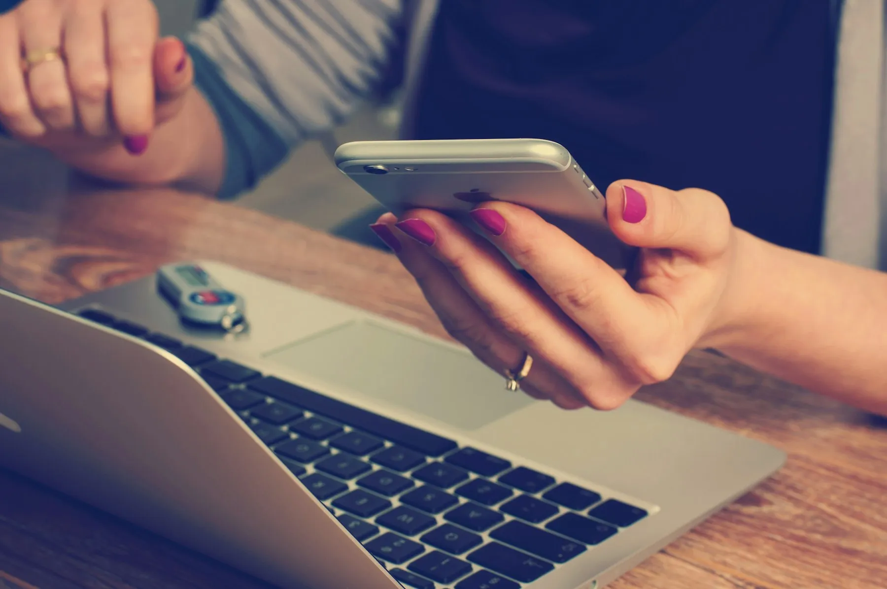 Hands holding a phone over a laptop