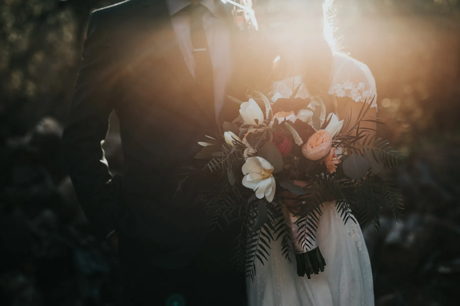 Bride and groom holding a bouquet in golden evening light